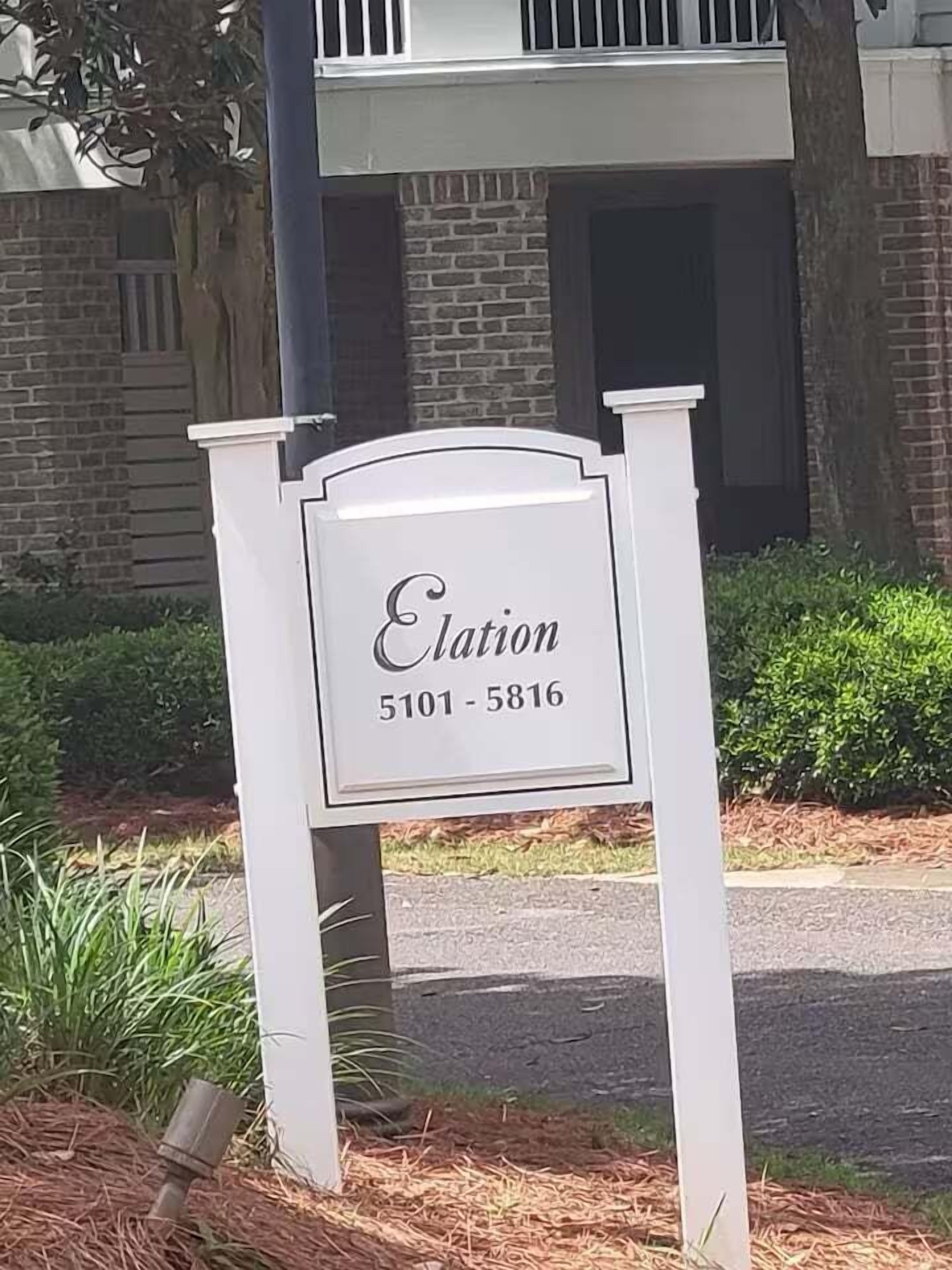 Ein weißes Schild mit dem Schriftzug 'Elation' und einer Telefonnummer.