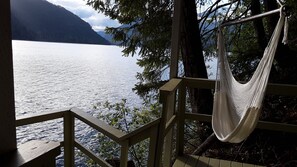 A hammock hanging on a wooden deck overlooking a lake with mountains in the background. - Spectacular Views from every room
Right on the Lake - Now with Air Conditioning! (Hoodsport)
