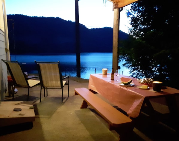 Sit and enjoy the serene lake view from this outdoor seating area, surrounded by a pergola and comfortable seating for two.