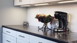 Una cocina con gabinetes blancos, encimera negra y cafetera.