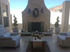 A cozy outdoor seating area with two sofas, a coffee table, and a fireplace. - Beautiful house steps from one of the most beautiful beaches in Baja. (Rosarito)
