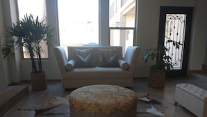 Ein Wohnzimmer mit einer Couch, einem Hocker und einem großen Teppich.