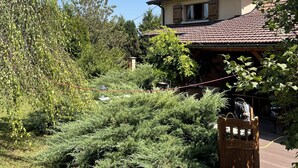 A house with a tiled roof, a wooden gate, and a garden with various plants. - Country property with covered terrace and large swimming pool (Charcier)