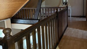 A wooden staircase with a dark railing leading to an upper level. - Country property with covered terrace and large swimming pool (Charcier)