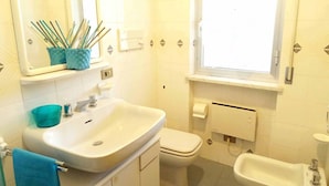 Baño con lavamanos, inodoro, bidé y ventana.