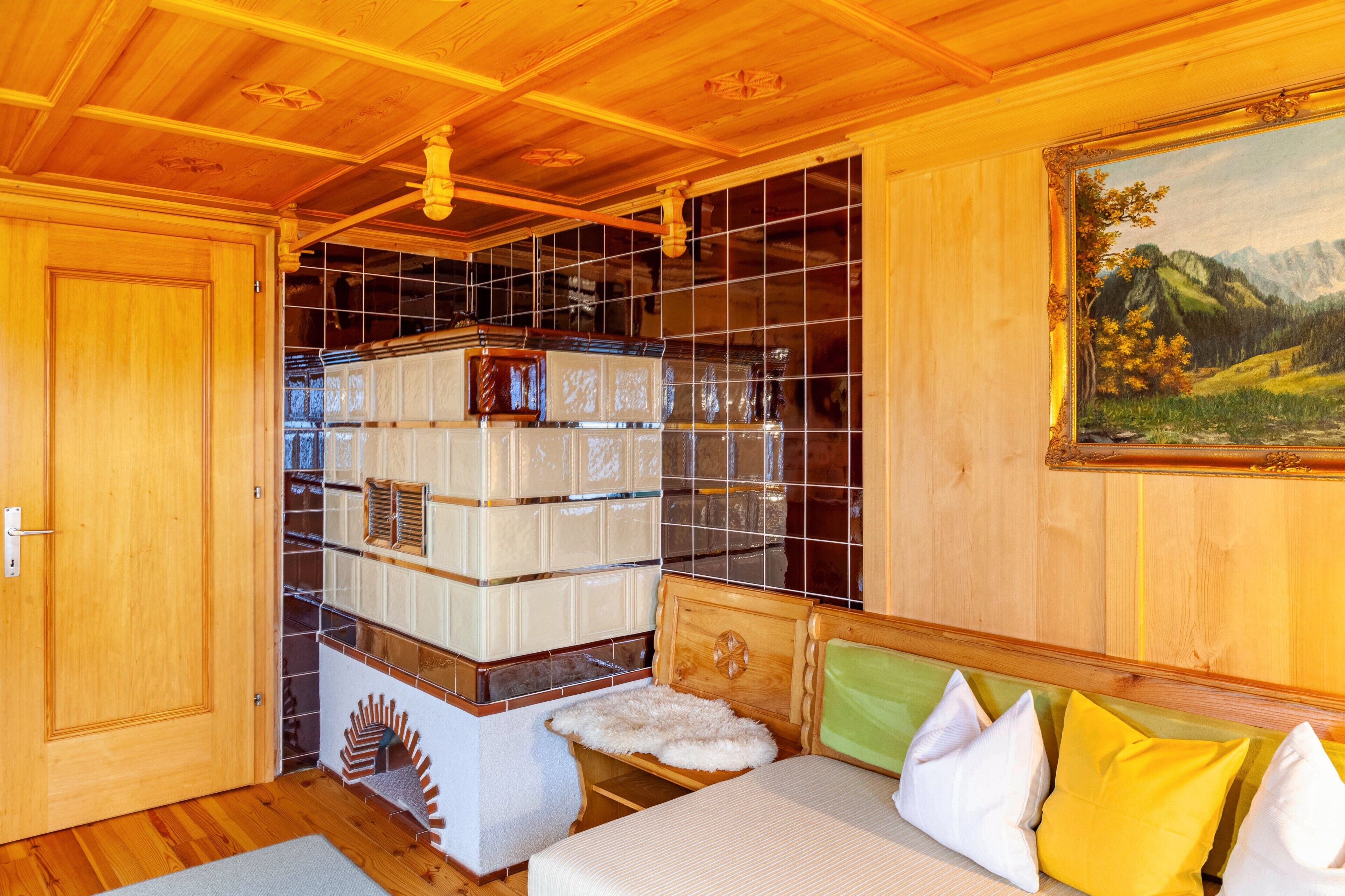 A wooden room with a bed, a painting, and a tiled wall with storage units.
