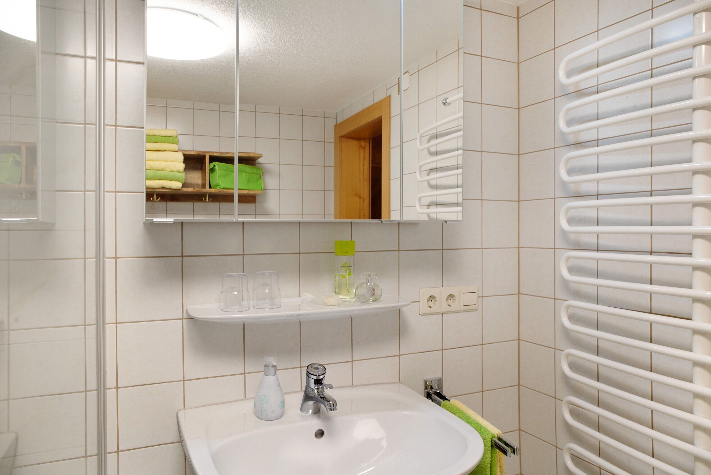 Een badkamer met een wit wastafelmeubel, spiegel en handdoekhouder.
