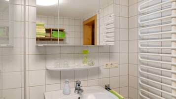 Een badkamer met een wit wastafelmeubel, spiegel en handdoekhouder.