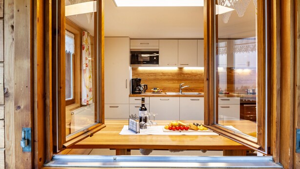 A modern kitchen with wooden cabinets, a stainless steel sink, and a breakfast setup on the counter. - Vacation Home "Dünser" with Mountain View, on a sunny slope. (Bizau)