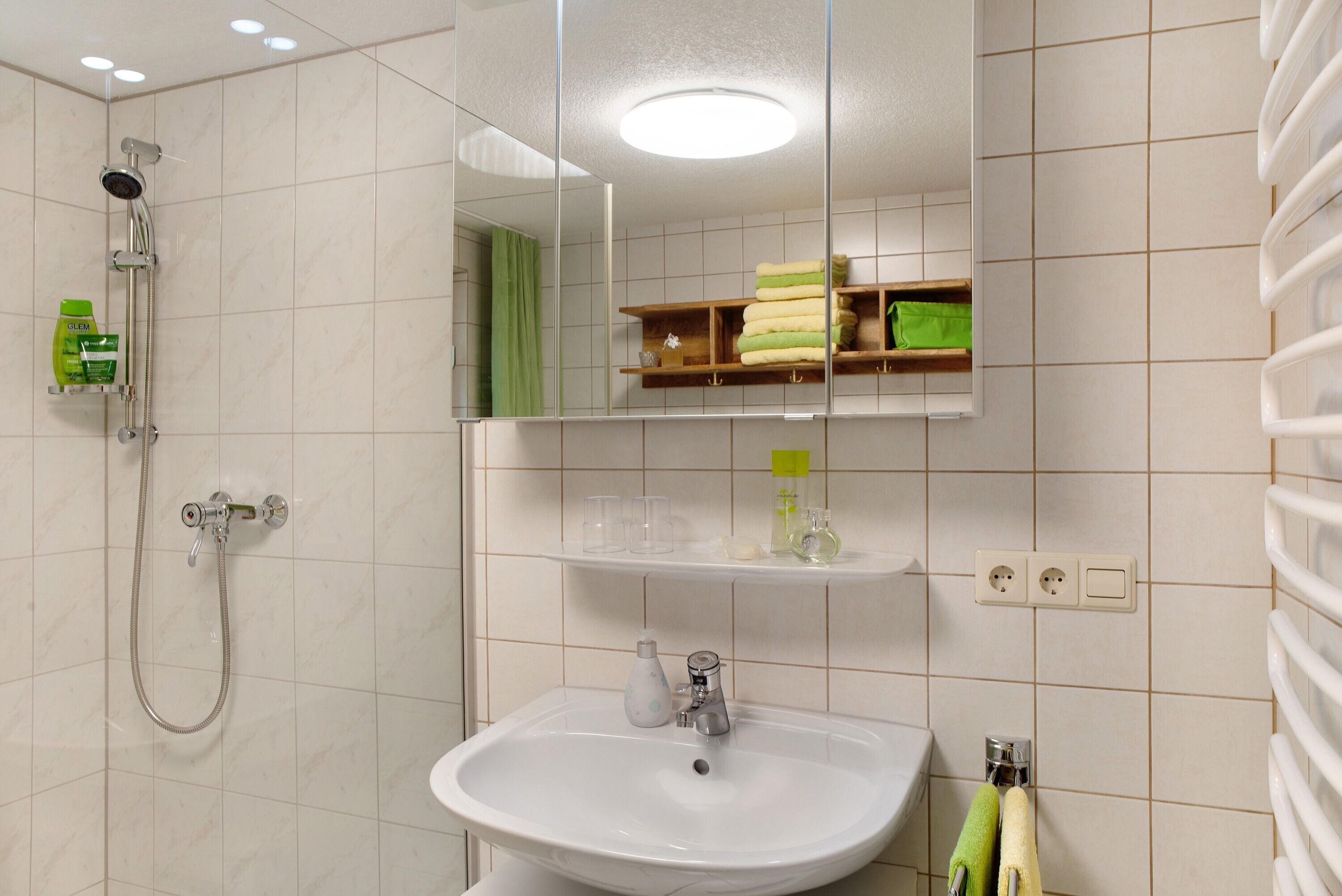A bathroom with a shower, sink, mirror, and towel rack.