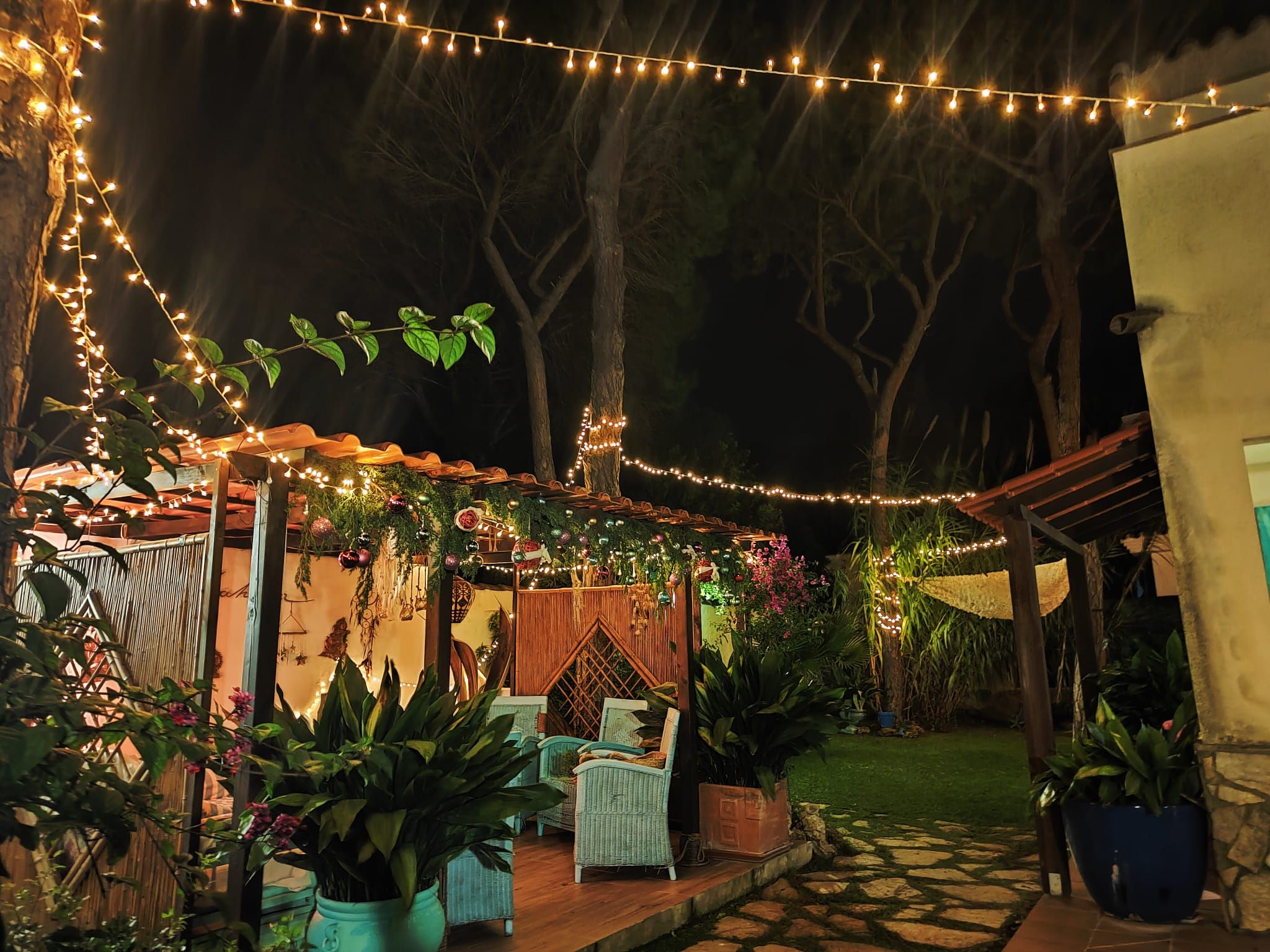An outdoor patio area with string lights, potted plants, and wicker furniture.