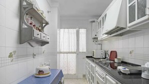 A compact kitchen with white cabinets, a microwave, a sink, and a table with a cake. - Centrally located apartment in Conil Pepa's House (Conil)