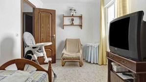 A room with a bed, a chair, a television, and a wooden door. - Centrally located apartment in Conil Pepa's House (Conil)