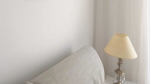 A hotel room with a bed, a bedside table with a lamp, a framed picture on the wall, and an air conditioning unit. - Centrally located apartment in Conil Pepa's House (Conil)