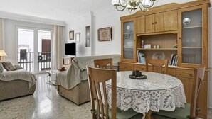 A living room with a dining table, chairs, a sofa, a TV, and a wooden cabinet with glass doors. - Centrally located apartment in Conil Pepa's House (Conil)