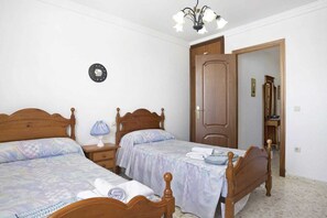 Une chambre à coucher avec deux lits en bois, une table de chevet avec une lampe, une armoire en bois et un miroir.