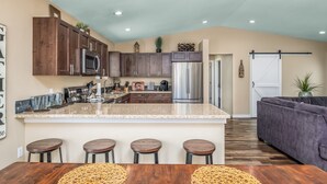 A modern kitchen with dark wood cabinets, stainless steel appliances, and a central island with bar stools. - Spacious home on a vineyard near Gorge Amp.,Leavenworth,chelan and Mission Ridge (East Wenatchee)
