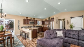 A modern kitchen with dark wooden cabinets, a central island, and a dining area with a wooden table and chairs. - Spacious home on a vineyard near Gorge Amp.,Leavenworth,chelan and Mission Ridge (East Wenatchee)