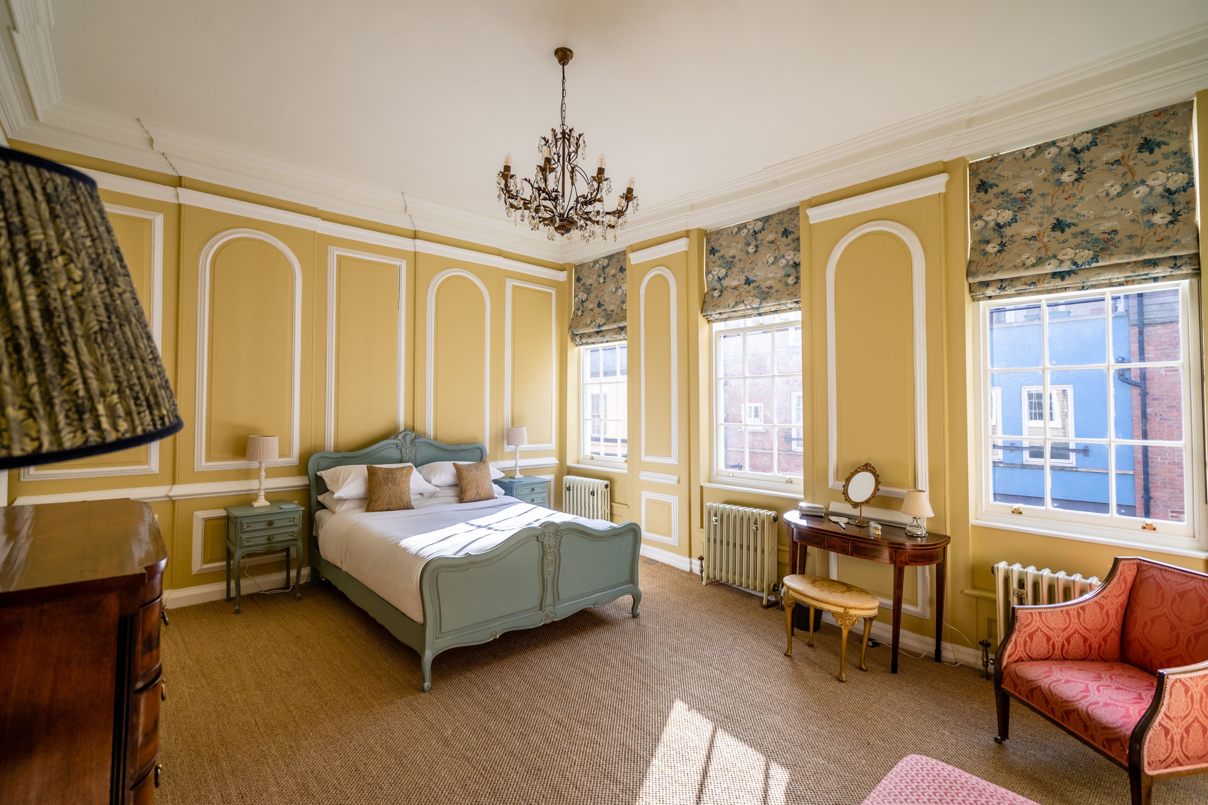 A classic room with a bed, a chair, a desk, and a radiator.