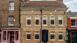 Un bâtiment traditionnel en briques, avec une porte bleu foncé, des fenêtres blanches et une devanture rose.