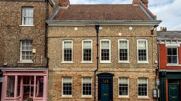 A traditional brick building with a dark blue door, white windows, and a pink storefront.