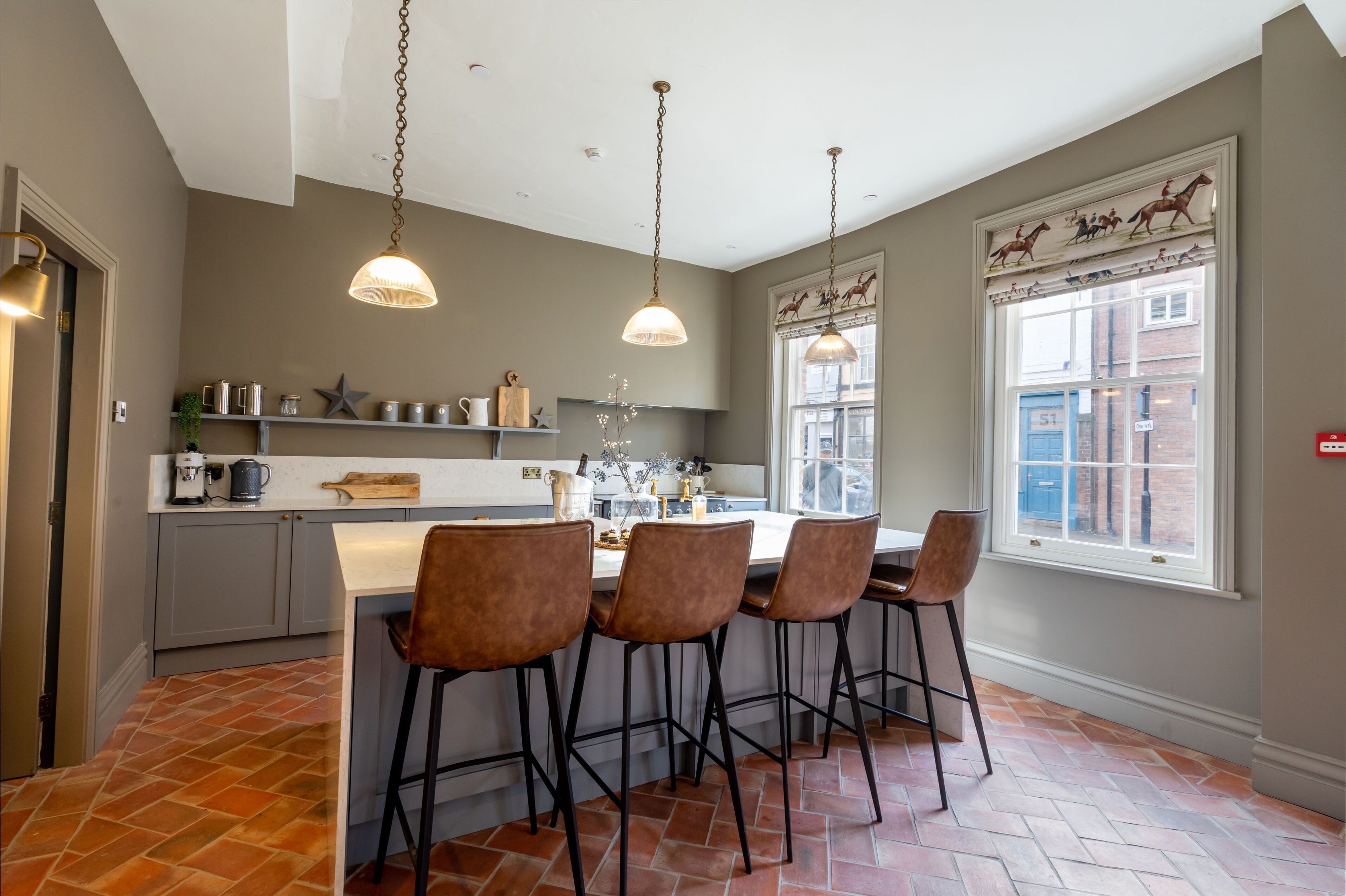 A kitchen with a central island, pendant lighting, and a window with a decorative view of horses.
