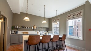 Une cuisine dotée d’un îlot central, de luminaires suspendus et d’une fenêtre offrant une vue décorative sur des chevaux.