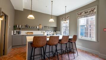 A kitchen with a central island, pendant lighting, and a window with a decorative view of horses.