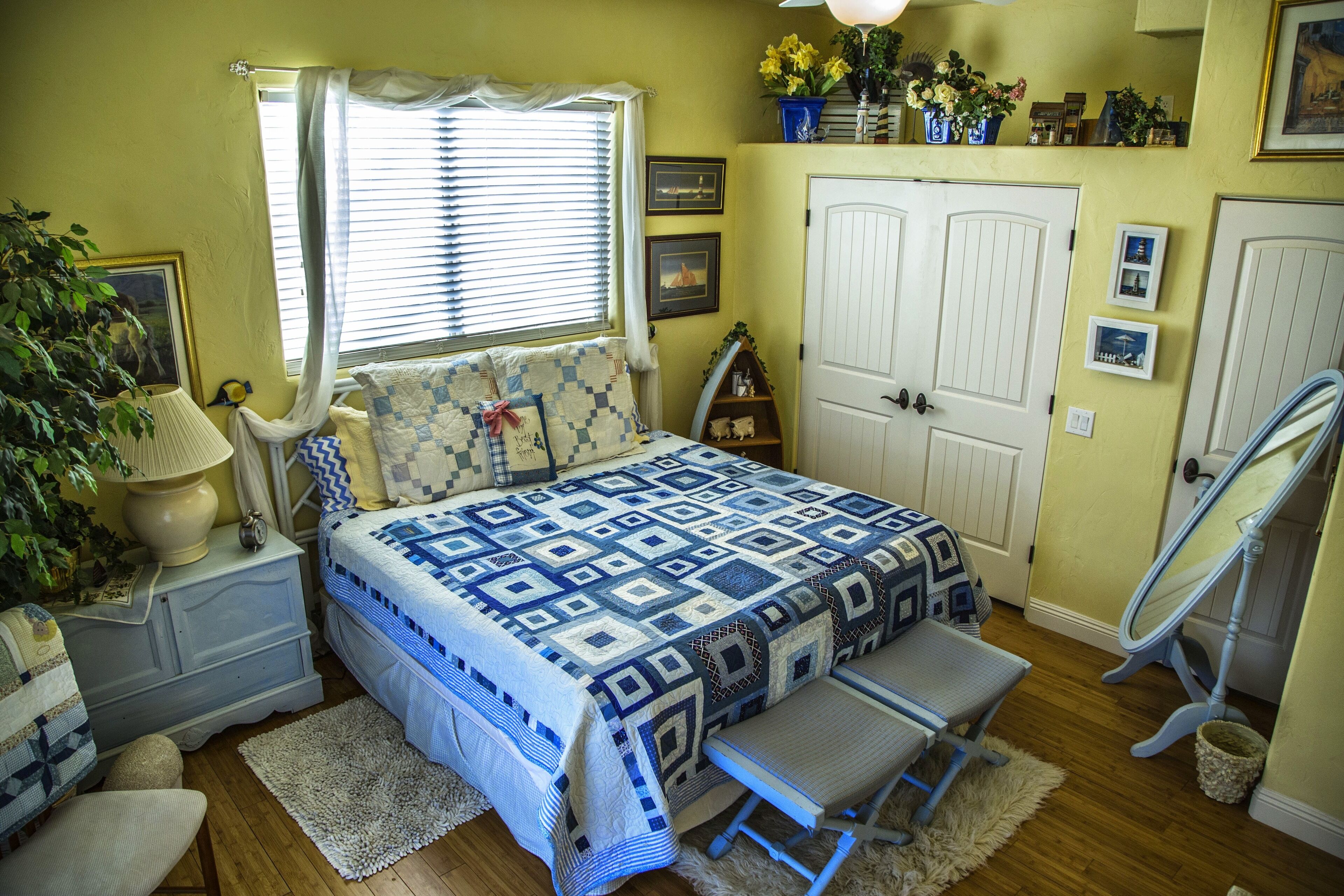 A bedroom with a bed, bedside tables, a chair, a mirror, and a dresser.