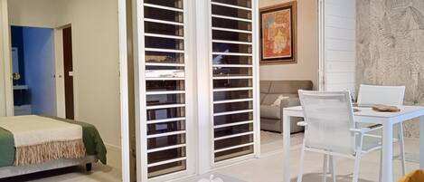 A modern living room with a sofa, a dining table with chairs, and a sliding glass door closet.