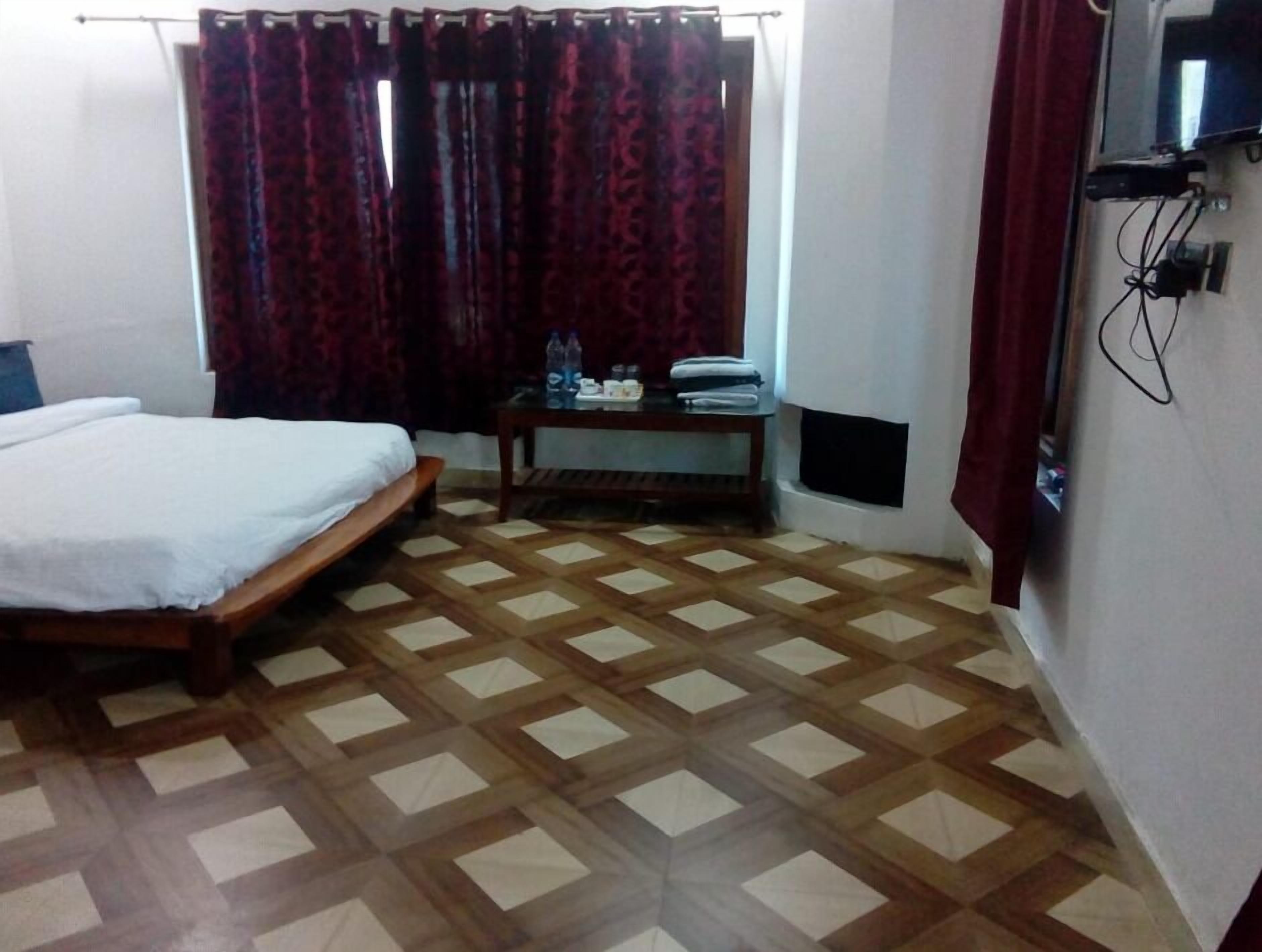 A room with a bed, a small table with toiletries, and a patterned floor.