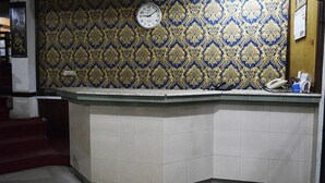 A reception desk with a clock, a telephone, and a small counter. - Shamrock Hotel (Lahore)