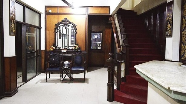 A room with a desk, chair, mirror, staircase, and a bed. - Shamrock Hotel (Lahore)