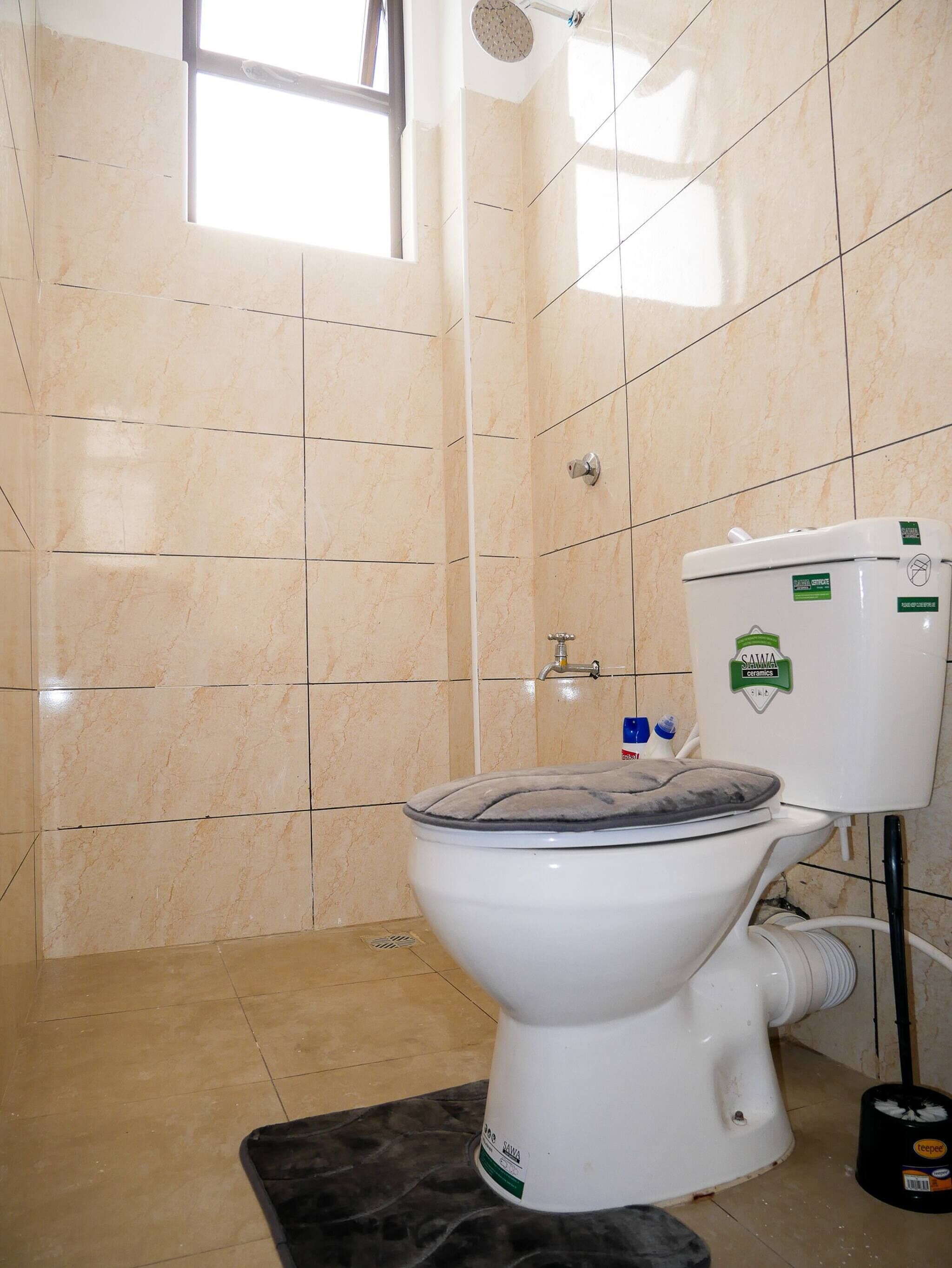 A bathroom with a toilet, a shower, and a window.