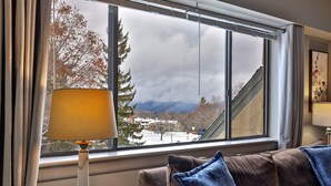A room with a large window, a sofa, and a table lamp. - The Hideaway Retreat at Mountain Green 1 BR/1 BA Condo, Steps to the Mountain, Amenities. (Killington)