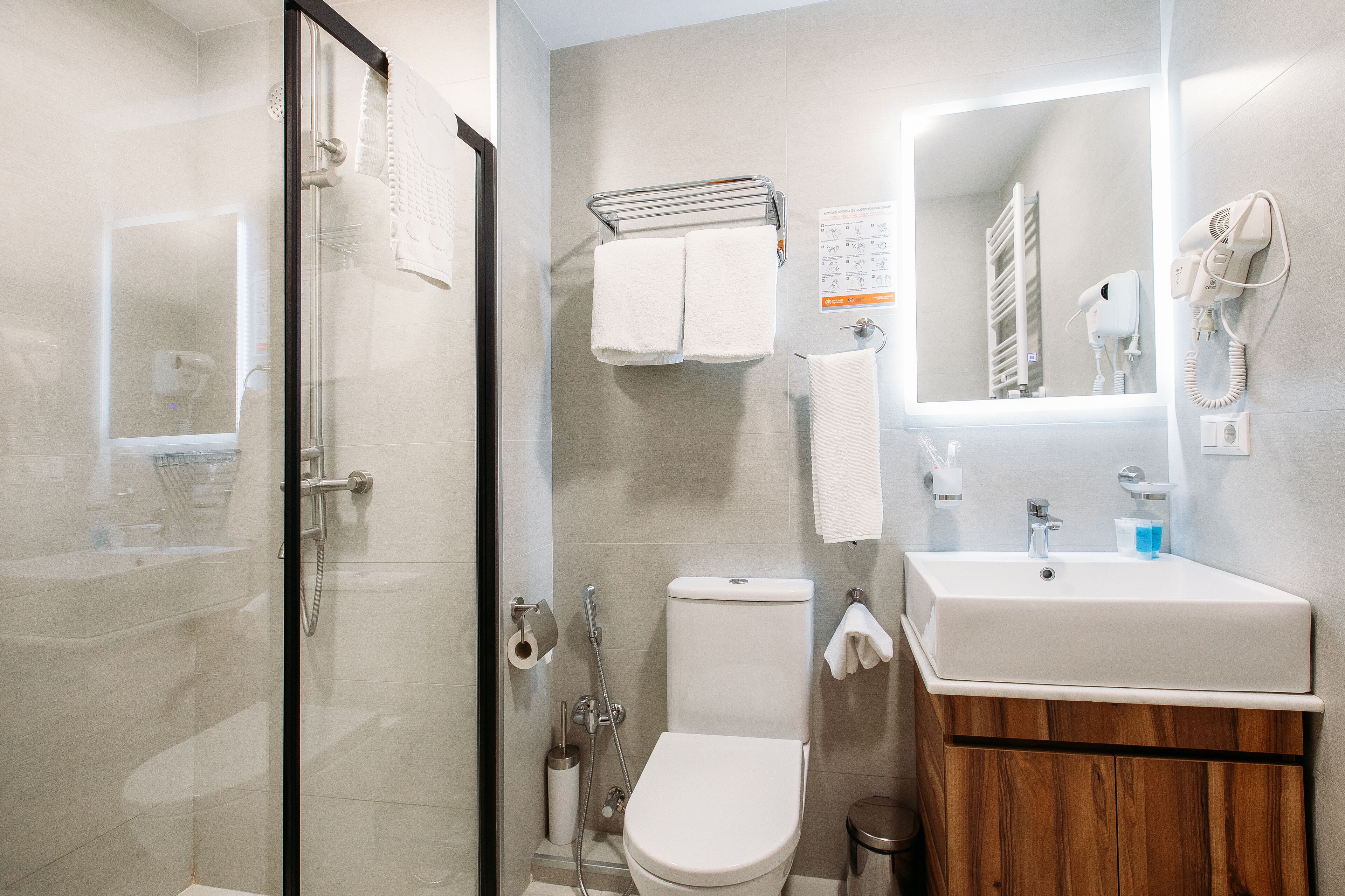 A modern bathroom with a glass-enclosed shower, a white sink, and a toilet.