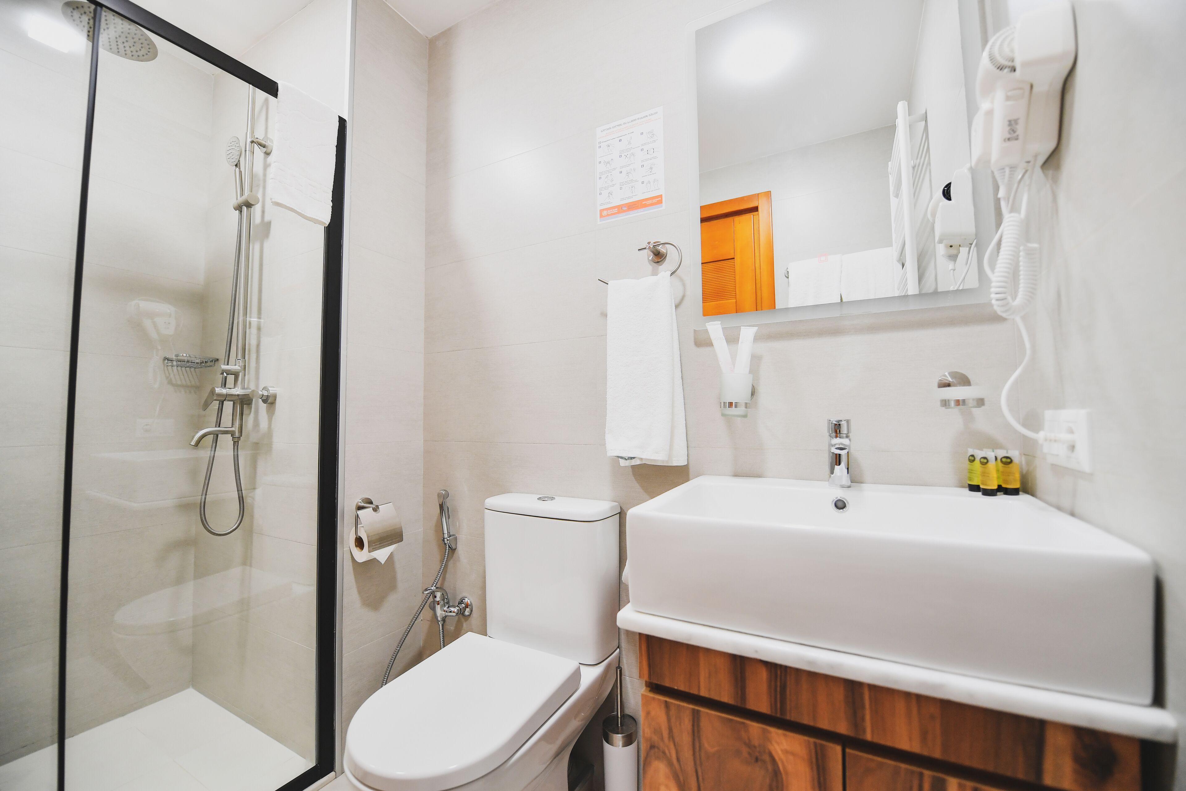 A modern bathroom with a glass-enclosed shower, a toilet, and a sink with a mirror above it.