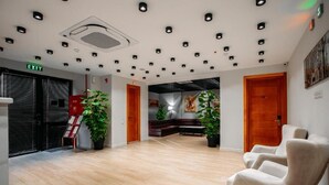 A spacious lobby with a wooden floor, a reception desk, and a seating area with a sofa and chairs. - Address Boutique Hotel (Tbilisi)