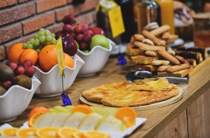 Un bufé con diversas frutas, pasteles y pizza.