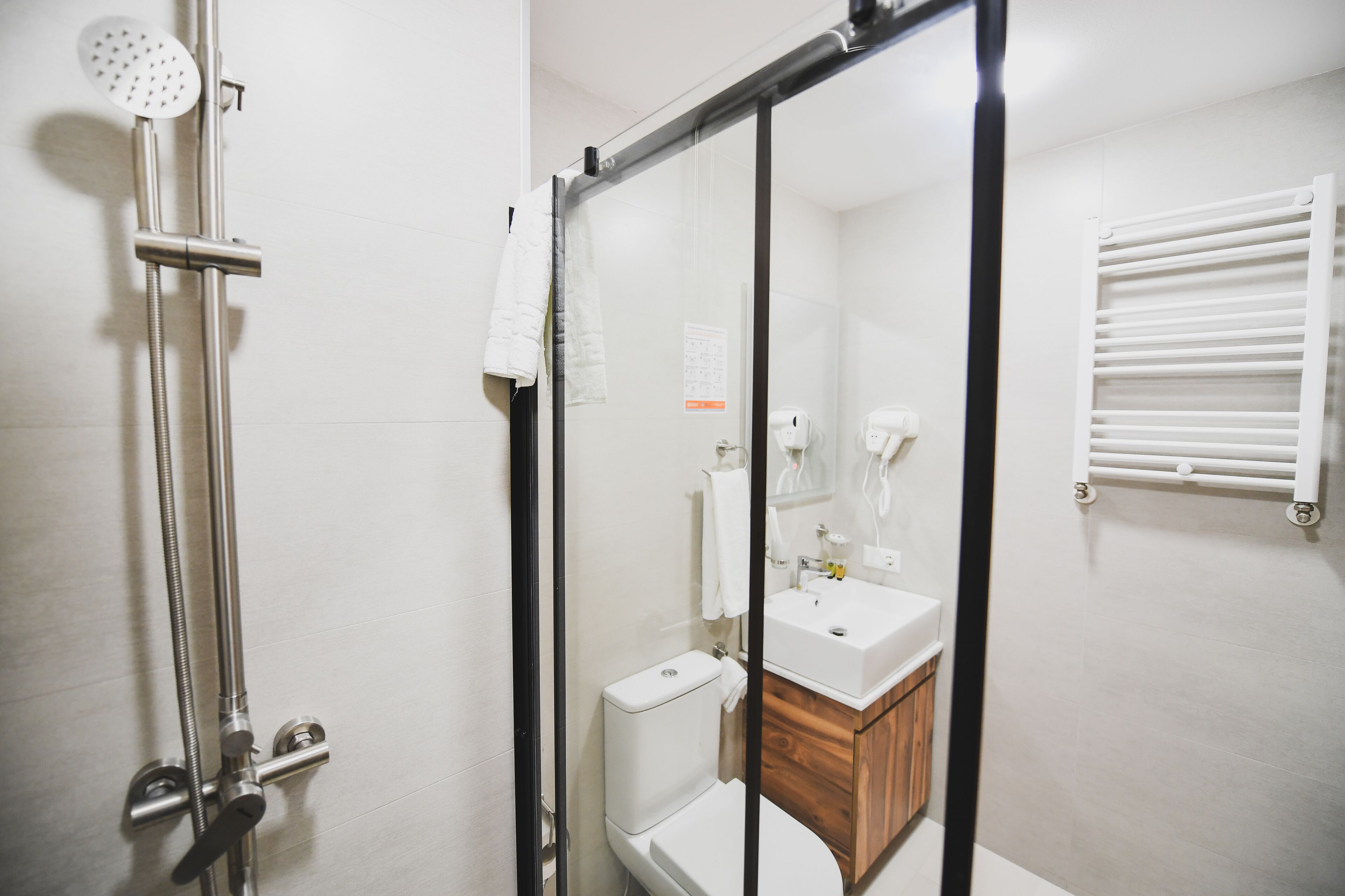 A modern bathroom with a glass shower enclosure, a white toilet, and a wooden vanity.