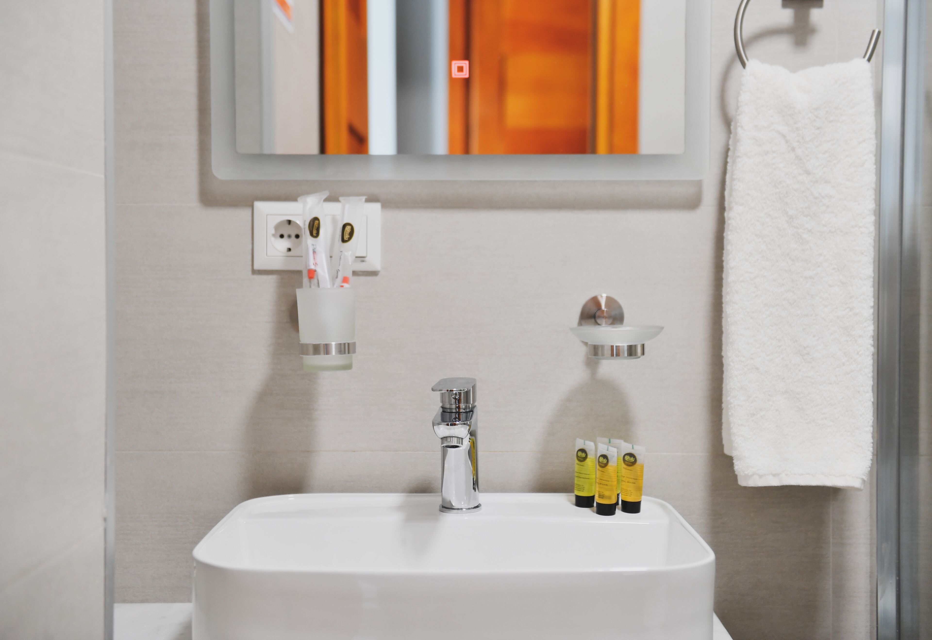A bathroom with a white sink, a mirror, and a towel hanging on a rack.