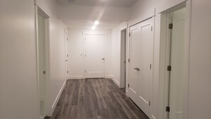 Un pasillo con paredes blancas, suelo de madera y una puerta en el centro.