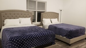Habitación de hotel con dos camas, cada una con cabecera y ropa de cama blanca.