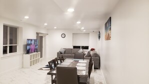 Una sala de estar moderna con una mesa de comedor, sofás y un televisor.