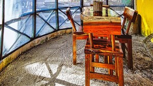 Una stanza con un tavolo e sedie in legno, ampie finestre e un tetto di paglia.