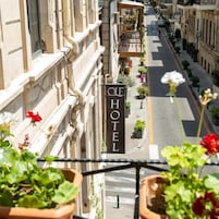 Een hotel met een bord met daarop 'HOTEL' op de gevel, omringd door een straat met plantenbakken en bloemen.
