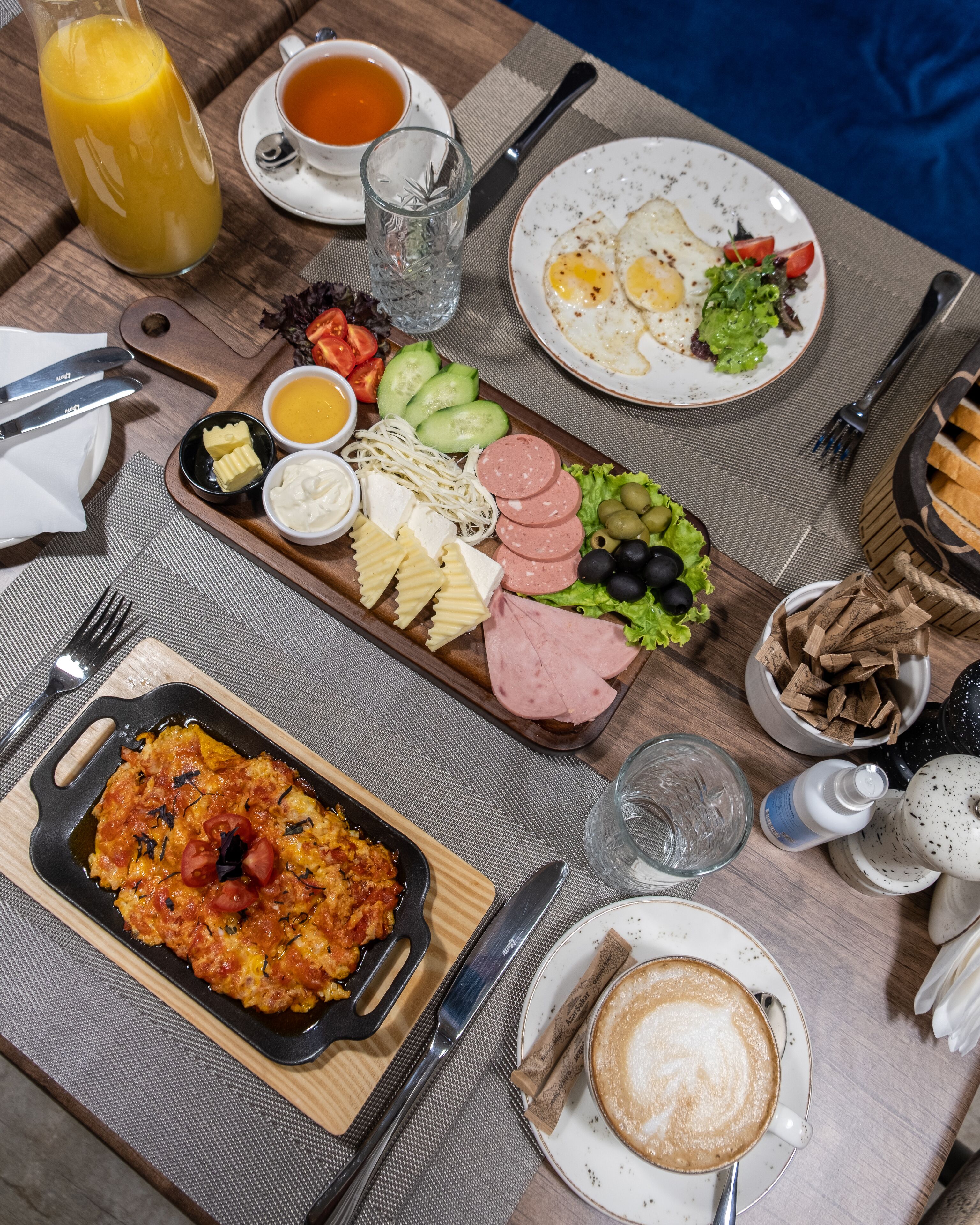 Une table de petit-déjeuner avec divers aliments, une tasse de café et un verre de jus d’orange.