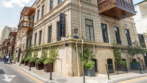Um edifício histórico com uma placa de hotel em destaque, janelas grandes e uma varanda com grades de madeira.