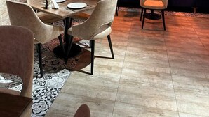 Um restaurante com parede de tijolos, assentos estofados azuis e um espaço de bar com garrafas.