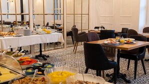A dining area with tables set for breakfast, featuring a variety of food items and a patterned floor. - HOTEL STARKL HERITAGE & UNIQUE (Bled)